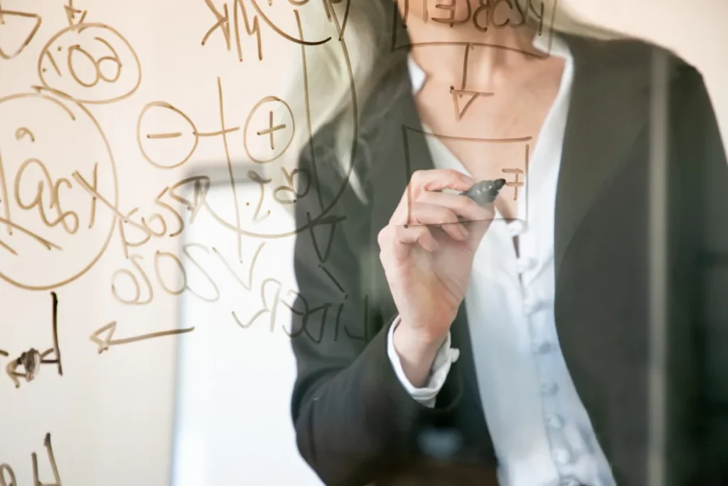 Femme écrivant sur tableau transparent avec diagrammes.