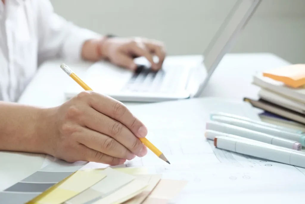 Personne travaille sur ordinateur avec plans et échantillons.